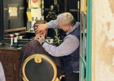 A barber carefully cuts a customer's hair in a traditional Lisbon barbershop, creating a classic look.