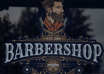 Detailed vintage barbershop logo featuring a bearded man on a reflective glass window.
