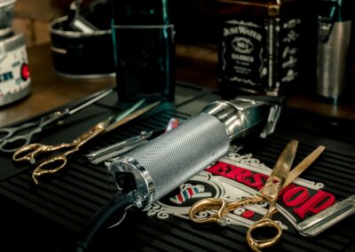 Close-up of barber tools including electric razor and scissors on a salon counter.