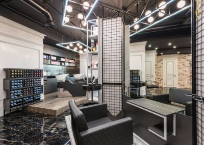 Black leather chair placed against mirror with reflection in stylish beauty salon with backwash chairs and abundance of cosmetology products