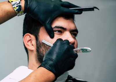 Close-up of a barber shaving a man's beard with precision in a contemporary barbershop setting.