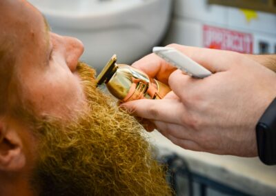 Barber expertly trims a man's beard using a razor in a close-up indoor setting.