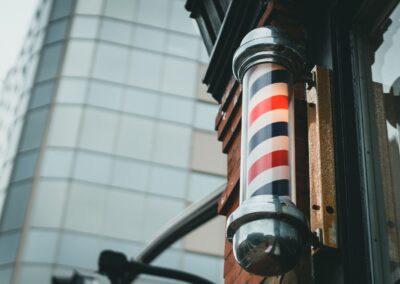 A retro barber pole mounted on a city building facade, symbolizing traditional barbering.